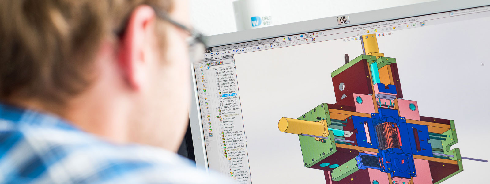 Employee in tool design in front of computer showing 3D image of die casting tool